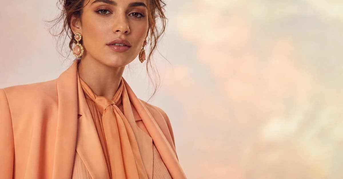 Woman in a soft peach top styled with warm neutrals and gold, colours that go with peach, by ToneLala